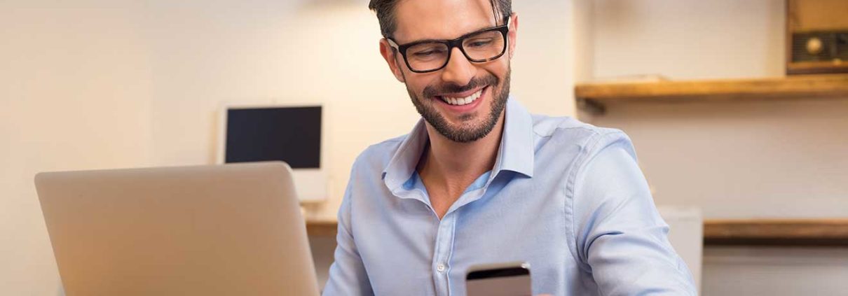 Young happy businessman smiling while reading his smartphone. Portrait of smiling business man reading message through email communication.
